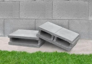 Dva betonové prázdné bloky na zemi před zdí.