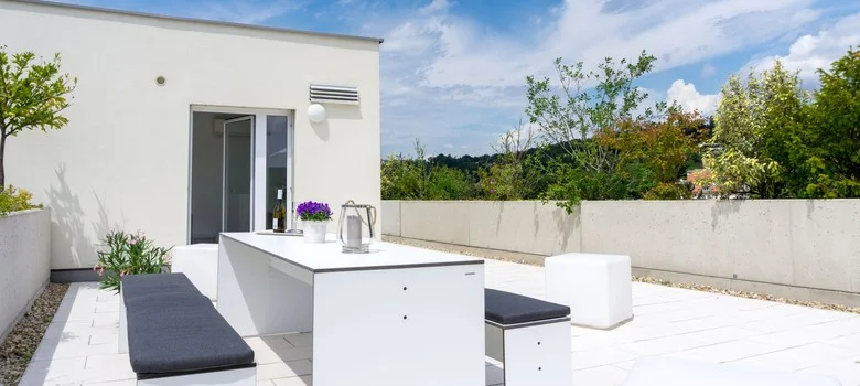 Moderní bílá terasa s velkými skleněnými balkónovými dveřmi.