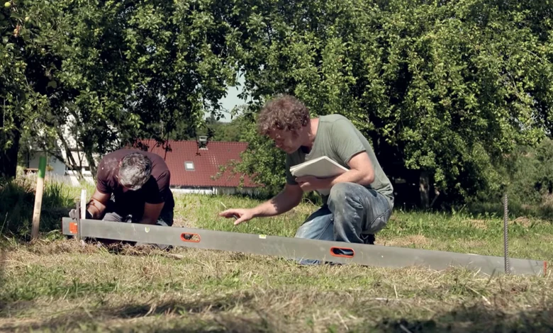Muži připravují základ domu pomocí úrovně pro betonování.