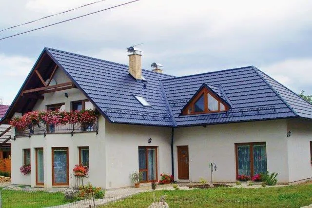 Moderní dům s plechovou střechou a květinovými boxy na balkónu.