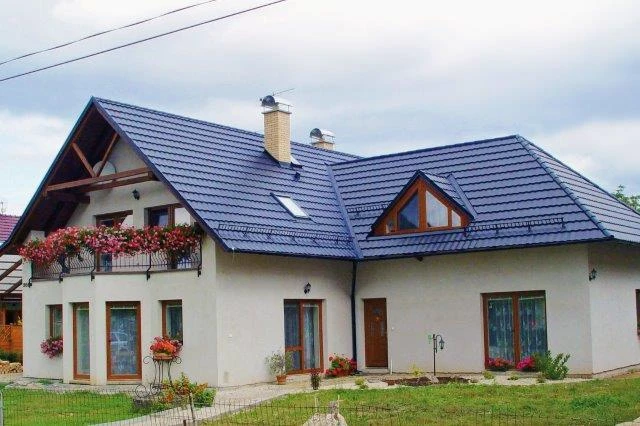 Moderní dům s tmavě modrou plechovou střešní krytinou.