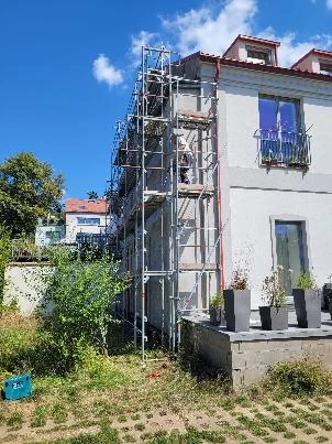 Dům v revitalizaci s montáží na fasádě pod modrou oblohou.