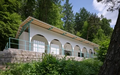 Bílá budova lesního koupaliště v Liberci obklopena stromy.