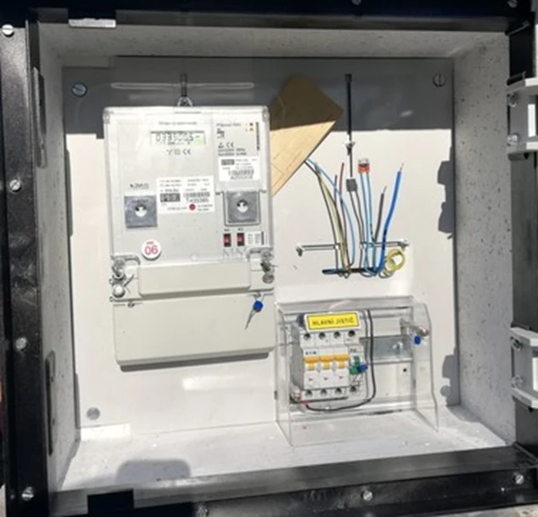 Vnitřek elektrického měřicího sloupku s elektroměrem a pojistkami.