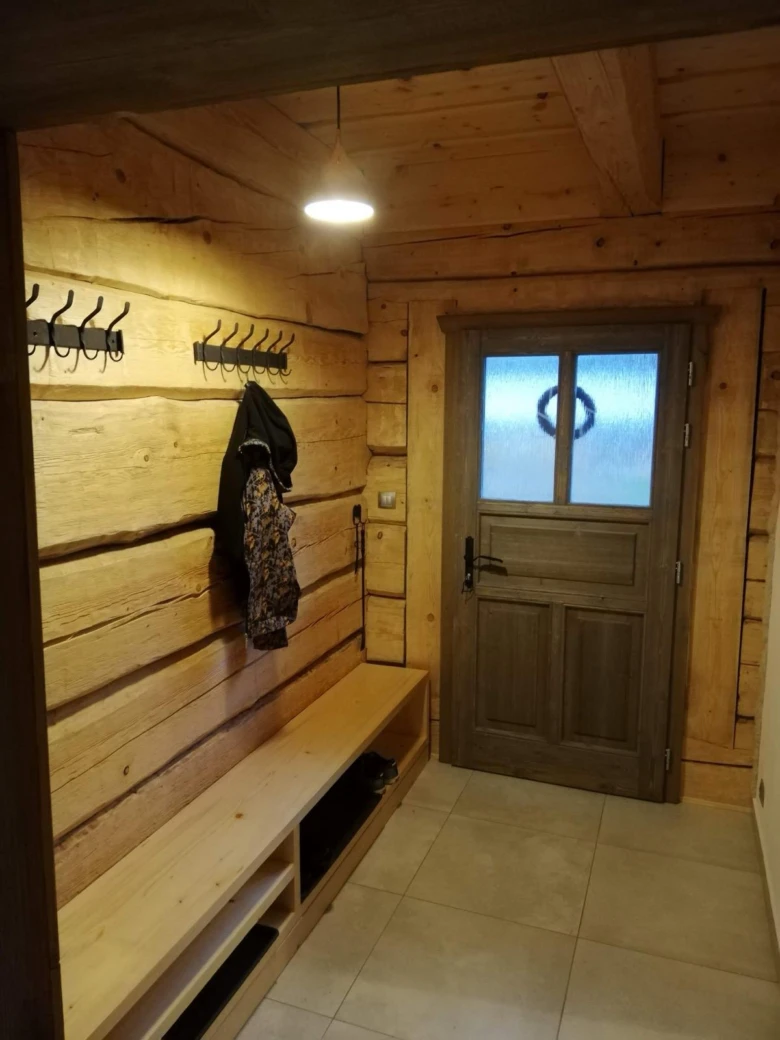 Vstup do roubenky s dřevěnou lavičkou a háčky na kabáty.