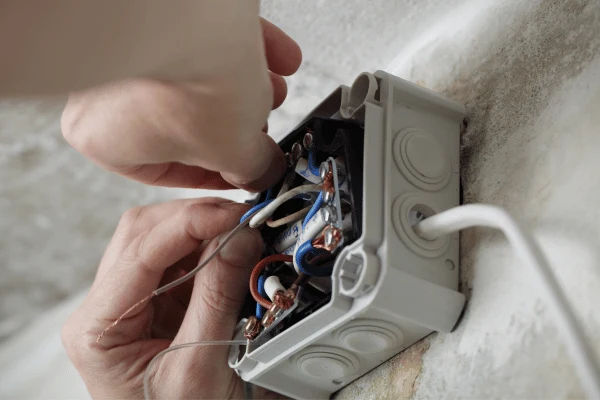 Ruční instalace elektrického vedení v domácnosti s odpojenými vodiči.