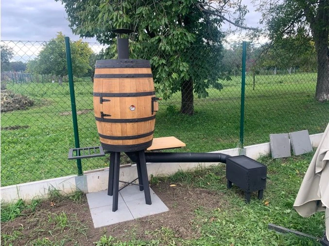 Udírna ze sudu s komínem venku na trávníku.