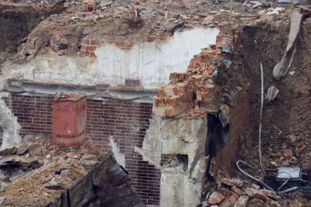 Zničená betonová konstrukce s cihlovými zdi po havárii.