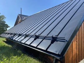 Trapezové plechy na střeše dřevěného domu s instalací.