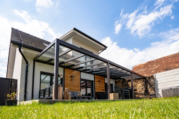 Moderní bioklimatická pergola připojená k domu na trávníku.