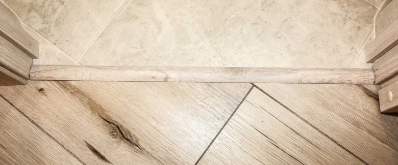 Dřevěná přechodová lišta mezi dřevěnou podlahou a dlažbou.