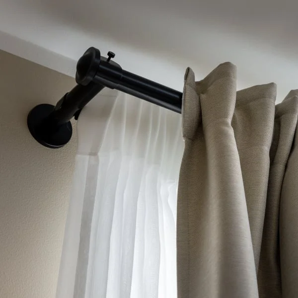 Černá garnýžová tyč připevněná k zdi bez vrtání.