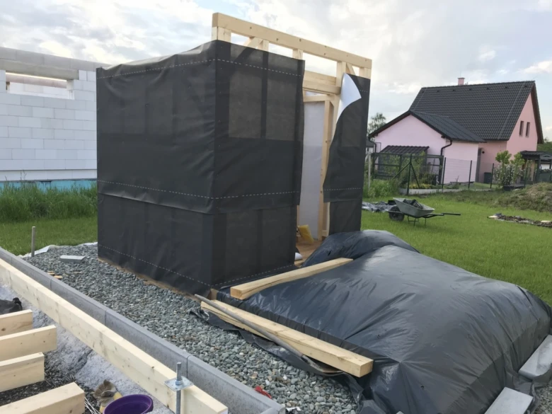 Stavba sauny na zahradě s dřevěným rámem a černou fólií.