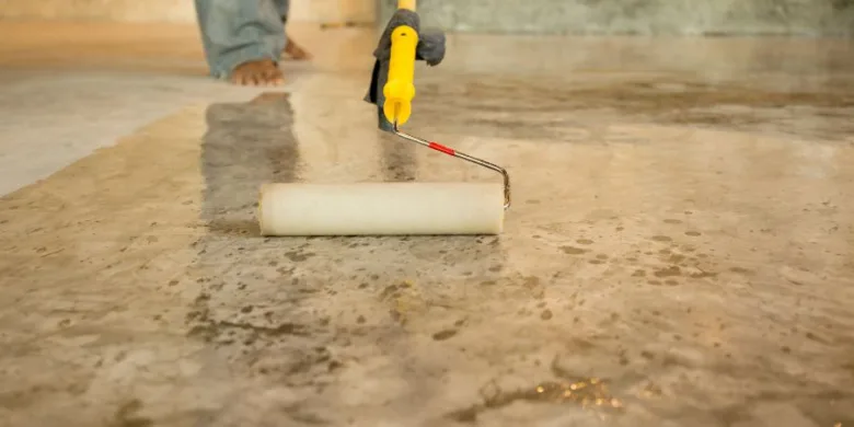Stěrka se nanáší válečkem na mokré betonové podlahy v koupelně.