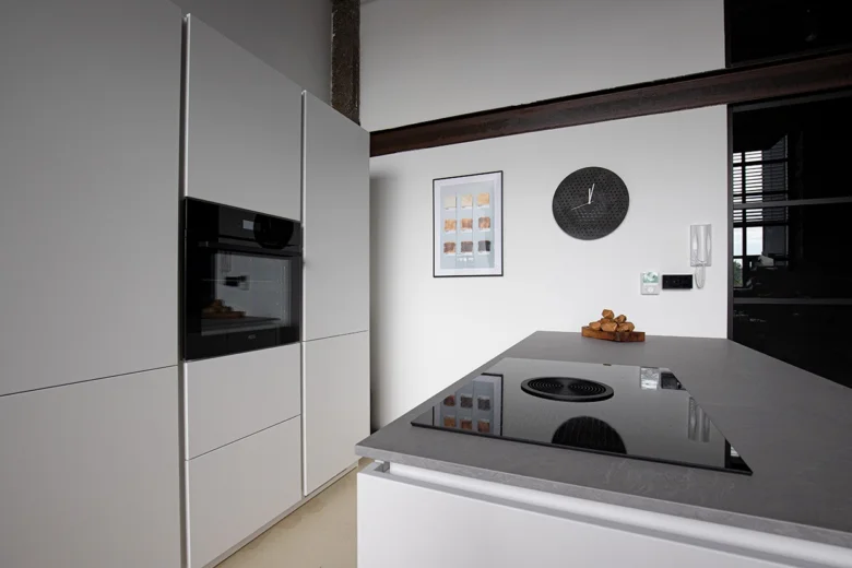 Moderní kuchyňský ostrůvek s vestavěnou troubou a indukční varnou deskou.