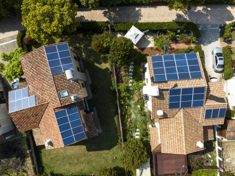 Dvě domy s fotovoltaickými panely na střechách z výšky.