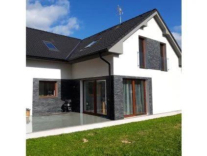 Moderní dům s kamenným obkladem na fasádě pod okny.