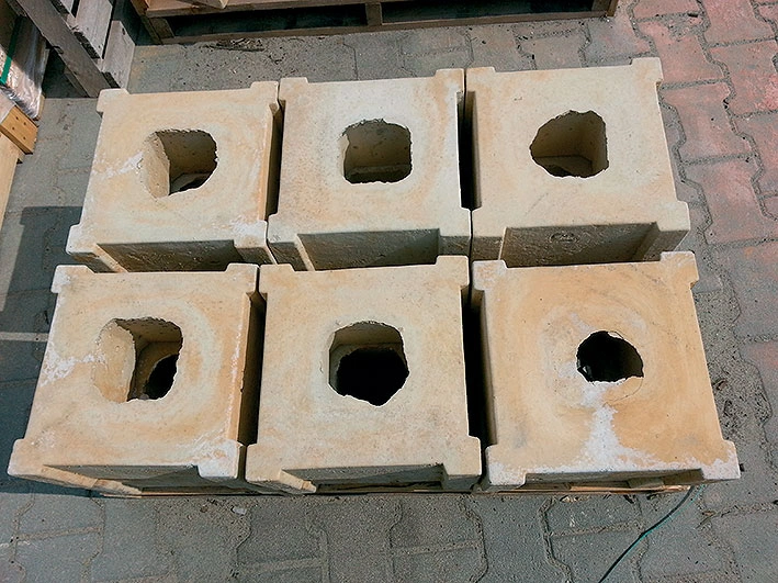Šest betonových tvarnic pro septik s otvory v horní části.
