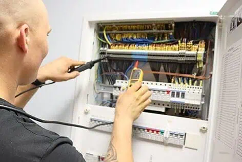 Elektrikář měří napětí v rozvaděči multimetrem.
