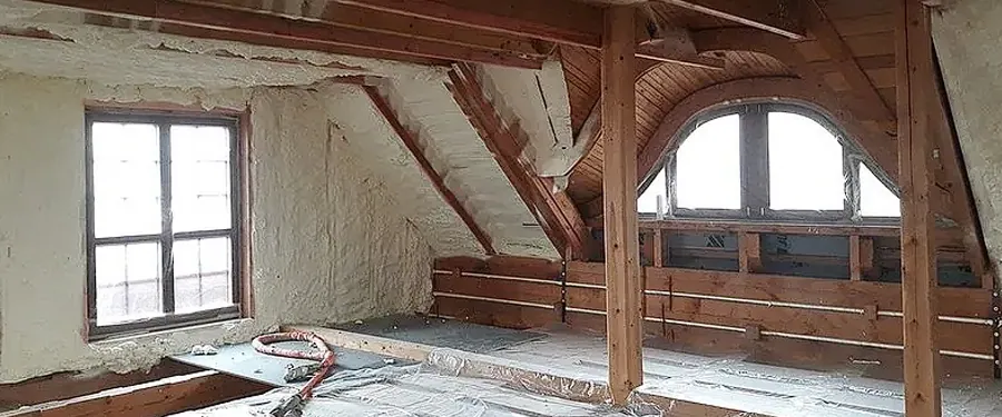 Zateplovací pěna na stěnách podkroví s dřevěným krovem.