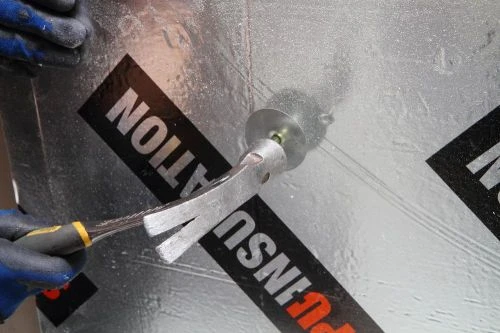 Instalace izolační pěny do sauny pomocí speciálního nástroje.