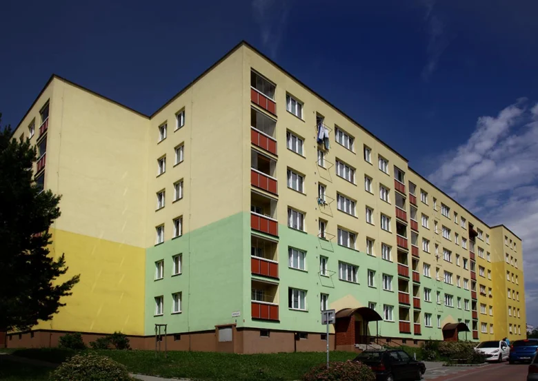 Barevná fasáda revitalizovaného bytového domu s balkony.