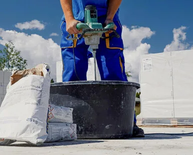 Stavebník míchá beton v kbelíku pro výrobu schodiště.