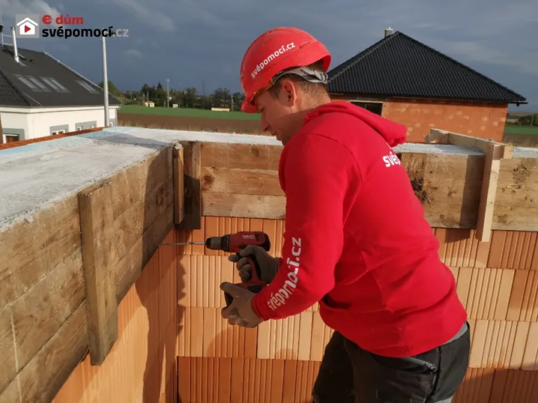 Stavebník montuje bednění betonového věnce pomocí vrtáku.