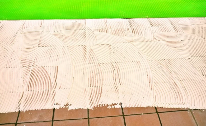 Príprava podlahy lepidlem pro vinylové dlaždice do koupelny.