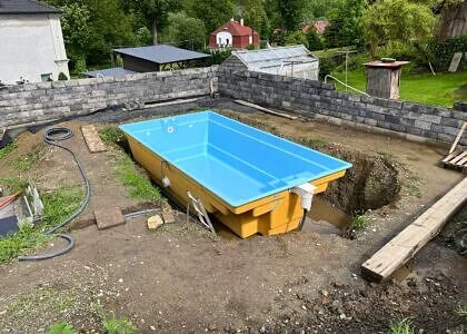 Žlutý nadzemní bazén se modrou vnitřností na zahradě.