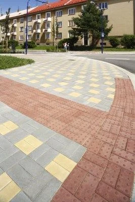 Různé typy betonové dlažby v geometrickém vzoru na chodníku.