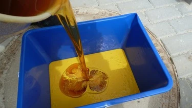 Nalévání epoxidové pryskyřice do modrého míchacího kbelíku.
