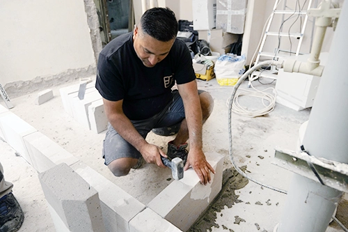 Muž kladí betonové cihly při rekonstrukci bytu.