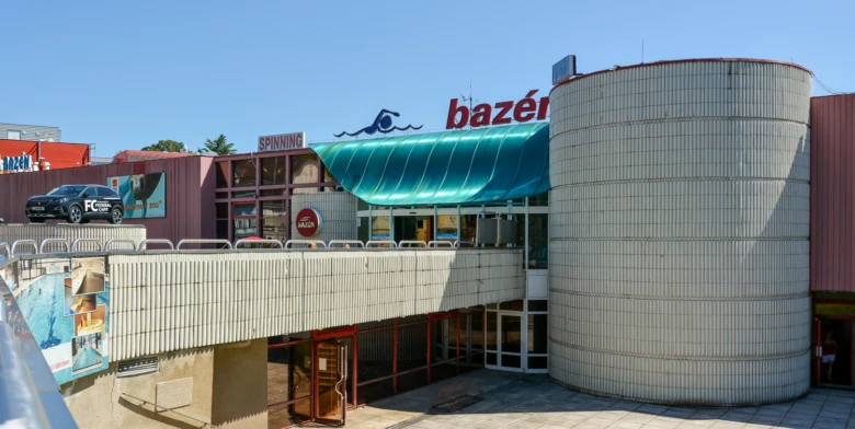 Exteriér plaveckého bazénu s velkým válcovým objektem v Liberci.