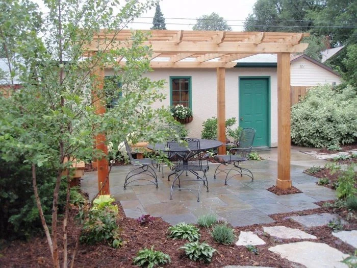 Dokončená dřevěná pergola s venkovním jídelním stolem na zahradě.
