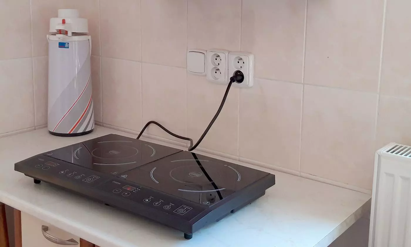 Indukční varná deska připojená k elektrické zásuvce v kuchyni.