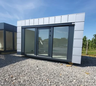 Moderní kontejnerový dům s velkými okny na štěrkové ploše.