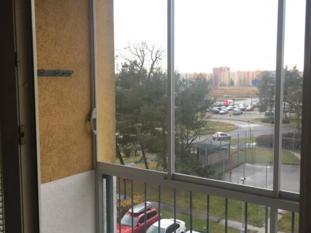 Moderní balkon s velkým zasklením výhledem na parkoviště.