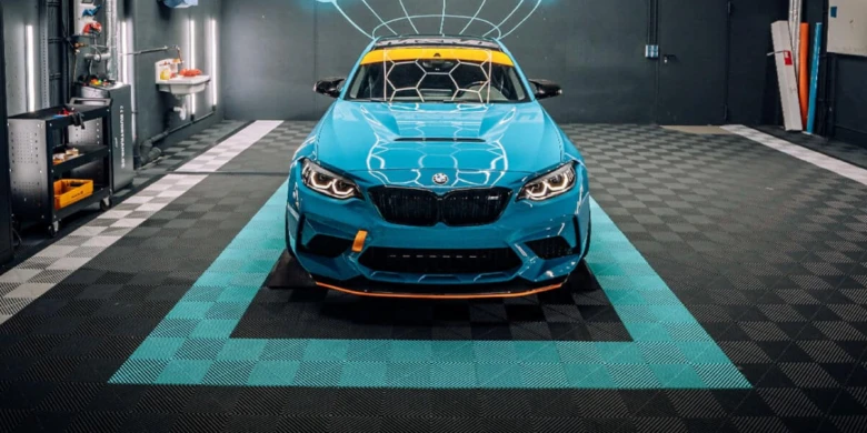 Modrá sportovní auto na dlažbě v garáži s geometrickým vzorem.