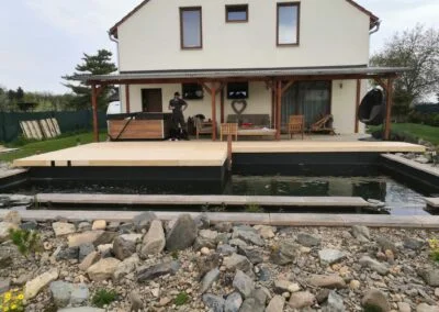 Dřevěná terasa ve svahu s přístupovými schody k domu.