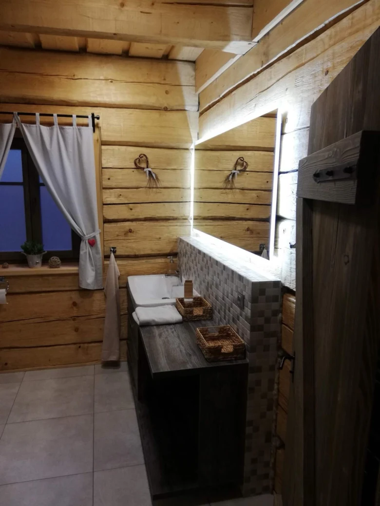 Moderní koupelna v roubené chalupě s dřevem a dlažbou.