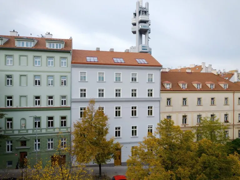 Řada barevných domů s různými štíty a střechami v Praze.