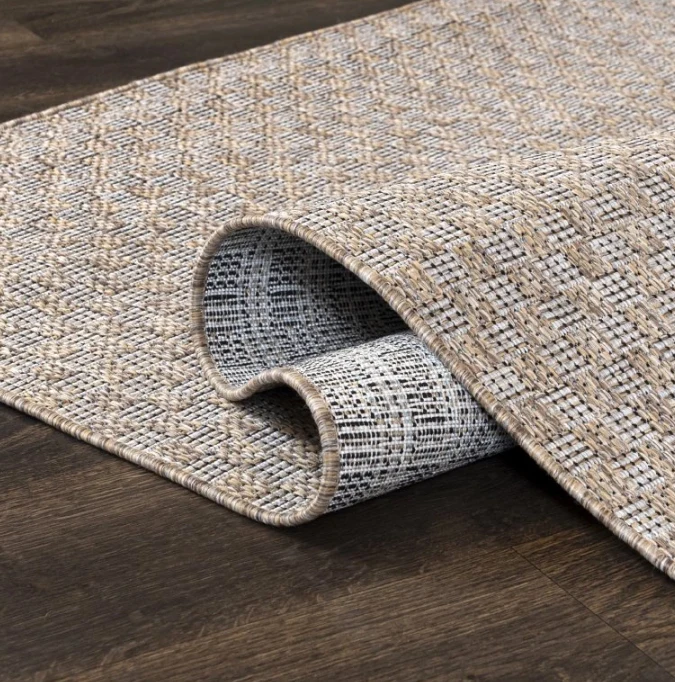 Detail texturovaného koberce na dřevěné podlaze.