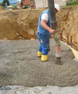 Pracovník míchá beton z pytlo na staveništi.