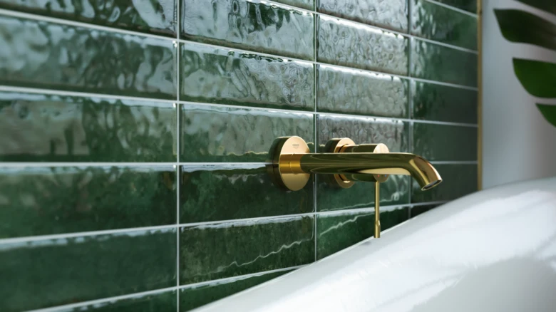 Green bathroom tiles and gold faucet