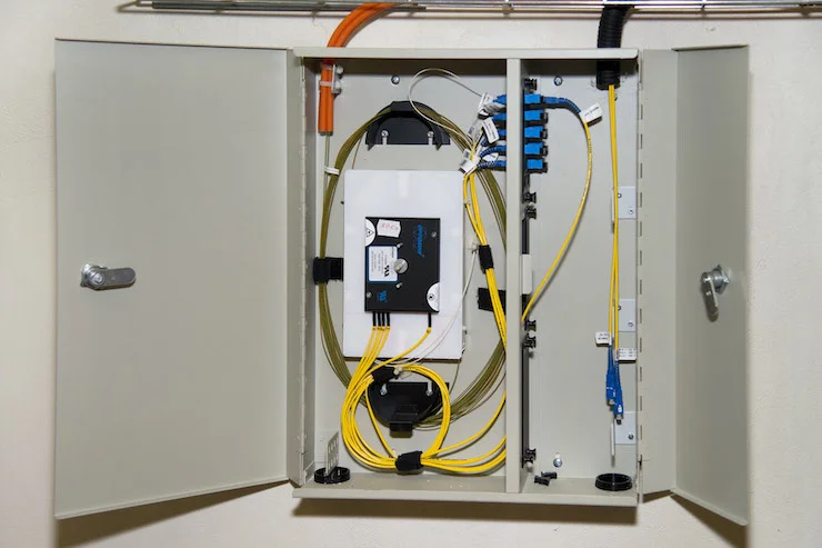 Vnitřní pohled na rozvaděč pro FTTH s žlutými optickými vlákny.