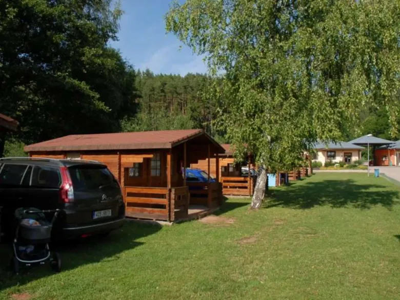 Dřevěné chaty na českém kempu s parkováním aut.