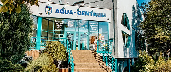 Vstup do plaveckého bazénu Aqua-Centrum v Jičíně s schodištěm a zelení.