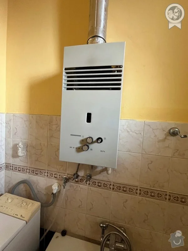 Plynový kotel na zdi v koupelně s hadicemi.