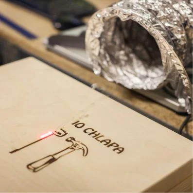 Laser gravíruje do dřeva nápis s ikonami nástrojů.